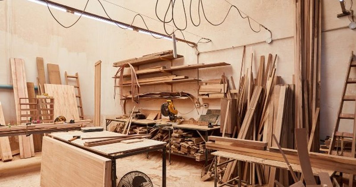 Tablones de diferentes tipos de madera — roble, pino, haya y nogal — apilados en taller de carpintería de Soria