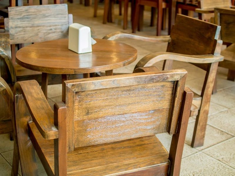 Sillas rústicas de madera maciza junto a una mesa redonda de pedestal